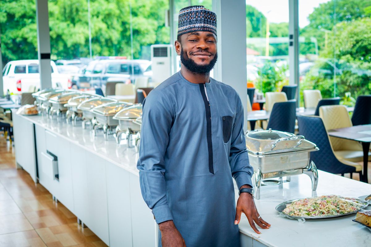 A smiling man beside a restaurant buffet in Abuja